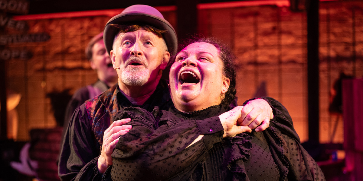 Two people stand together in embrace laughing.