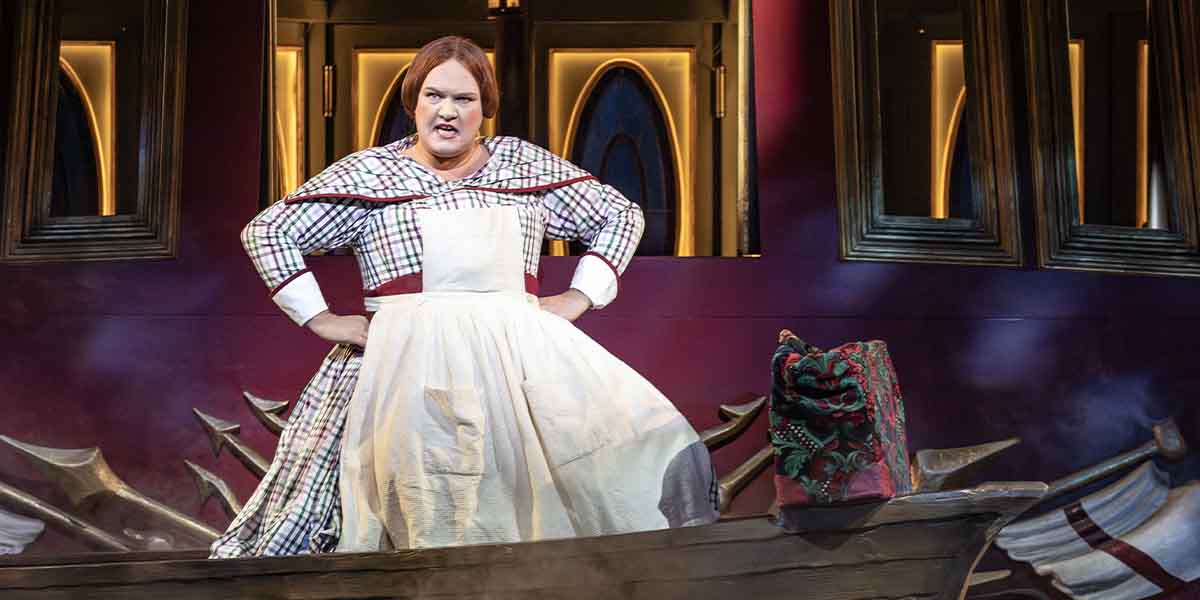 Rhonda Browne performs in a white dress with a plaid pattern, expressing strong emotions on stage.