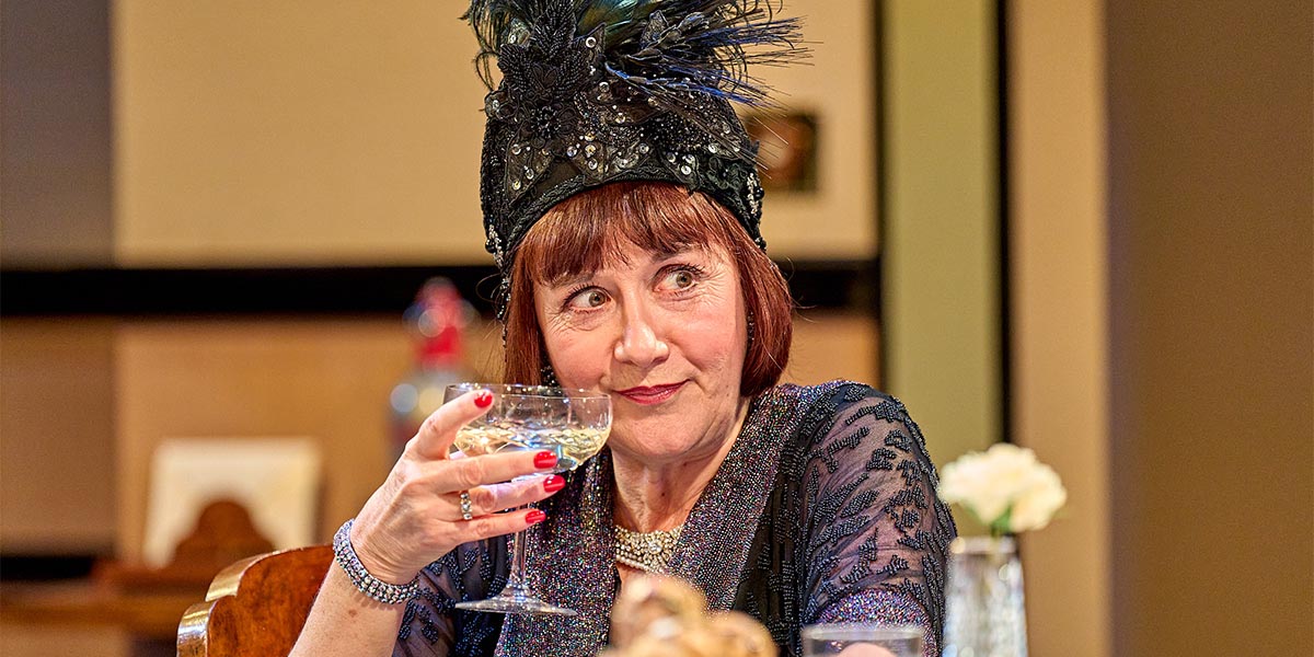 Alexandra Gilbreath and Jane Banbury perform on stage in dramatic costumes, with a dark, moody backdrop.