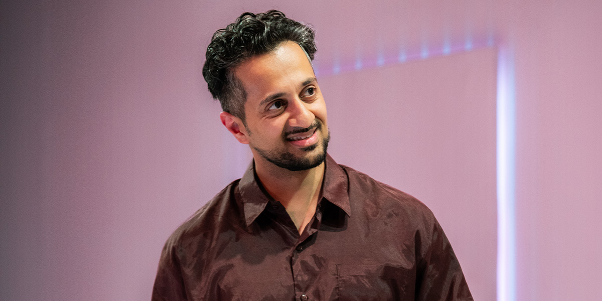 Fayez Bakhsh stands in a textured grey suit against a soft-focus laundry backdrop.