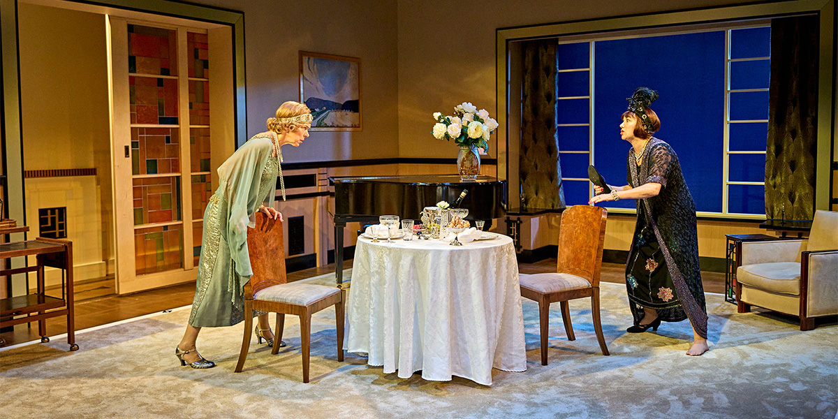 Janie Dee as Julia Steroll and Alexandra Gilbreath as Jane Banbury, both in elegant costumes, on stage.