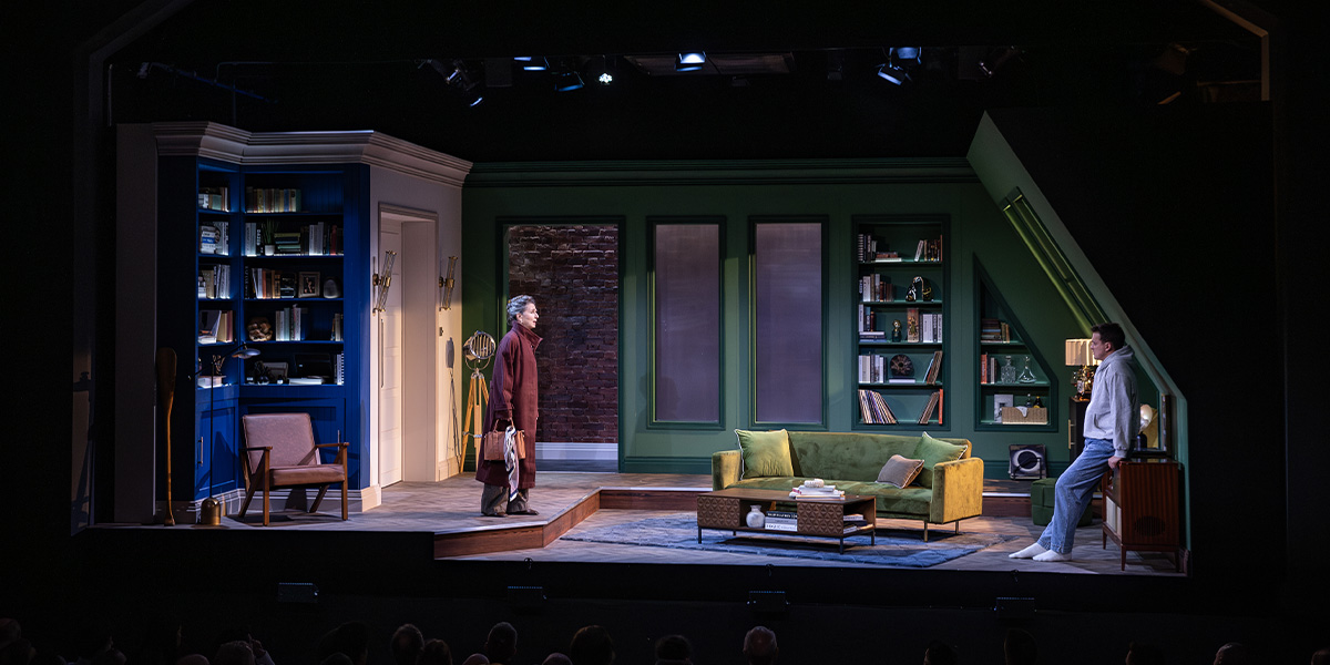 Two people stand on stage in an emotional scene.