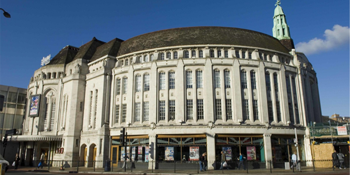 Broadway Theatre's ornate white facade with a domed roof against a clear blue sky.