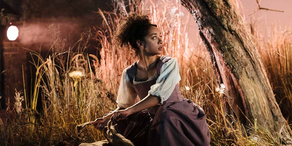 A person wearing a dark dress looks over their shoulder.