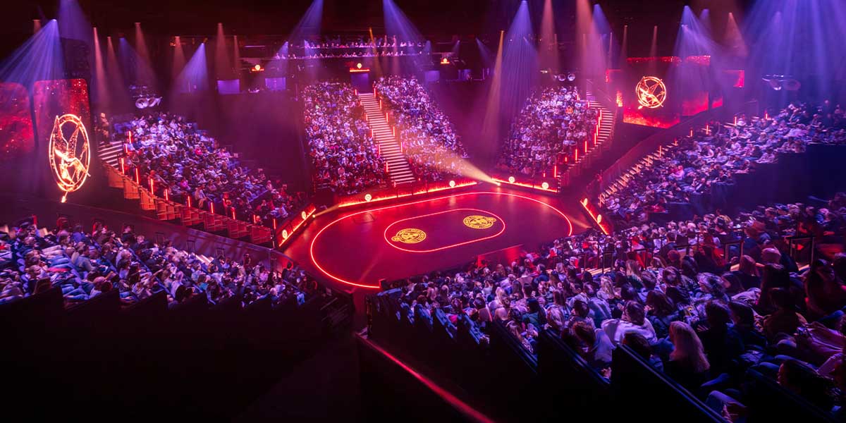 A vibrant stage set for "The Hunger Games," featuring elaborate props and dramatic lighting effects.