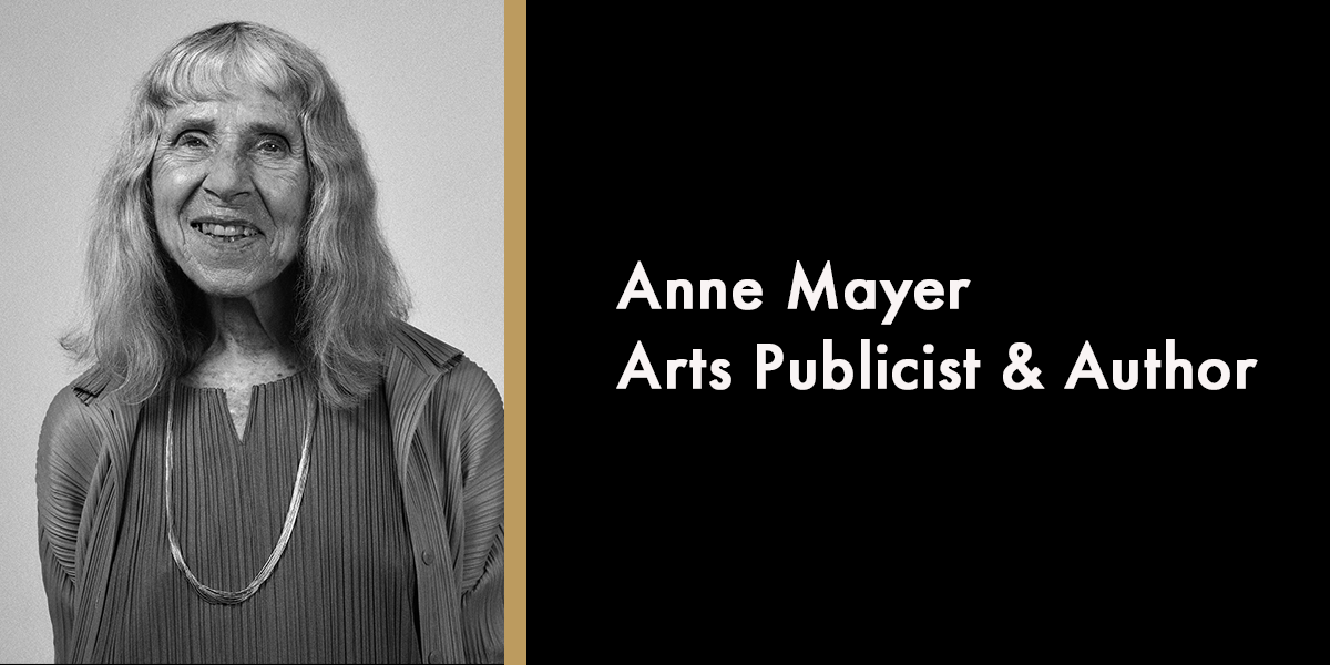 A portrait of Anne Mayer, smiling, with a soft-focus background and warm lighting.