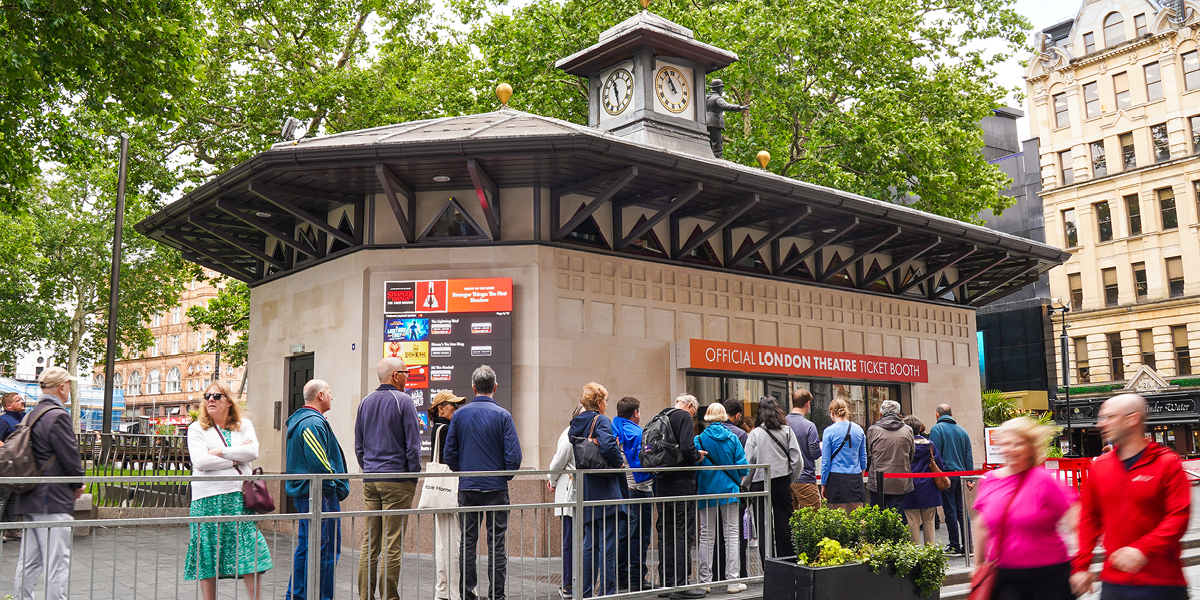 A vibrant booth display for Official London Theatre featuring colourful posters and promotional materials.
