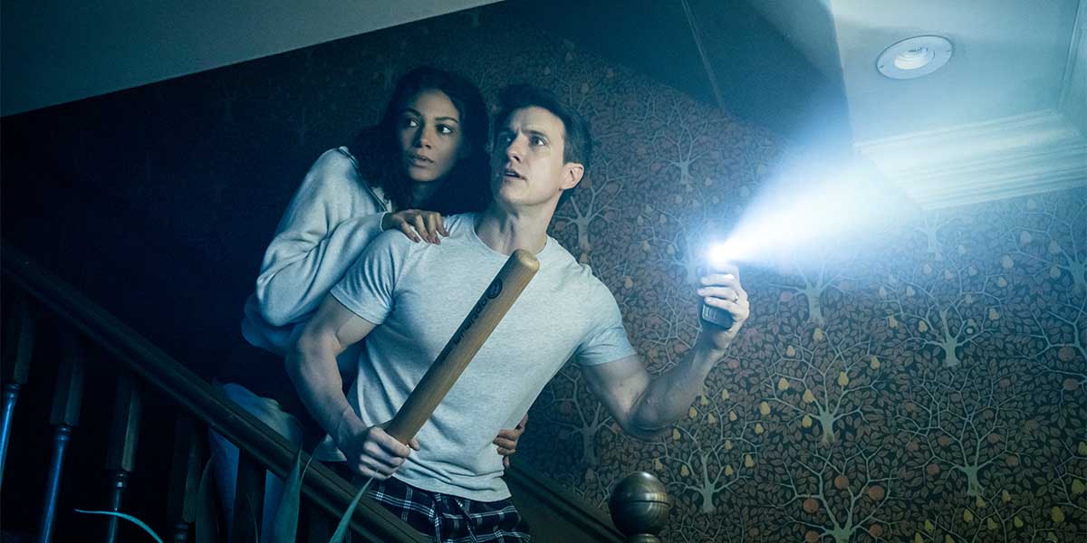 A scene from "Paranormal Activity" featuring Johan Persson, with dim lighting and eerie shadows in the background.