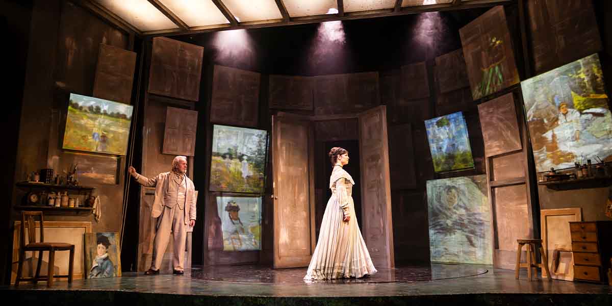 Jeff Shankley and Brooke Bazarian perform on stage, surrounded by projected artworks and wooden panels.