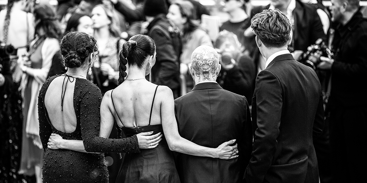 A black and white photo of the cast and creatives of Sunset Boulevard being photographed on the Olivier Awards green carpet
