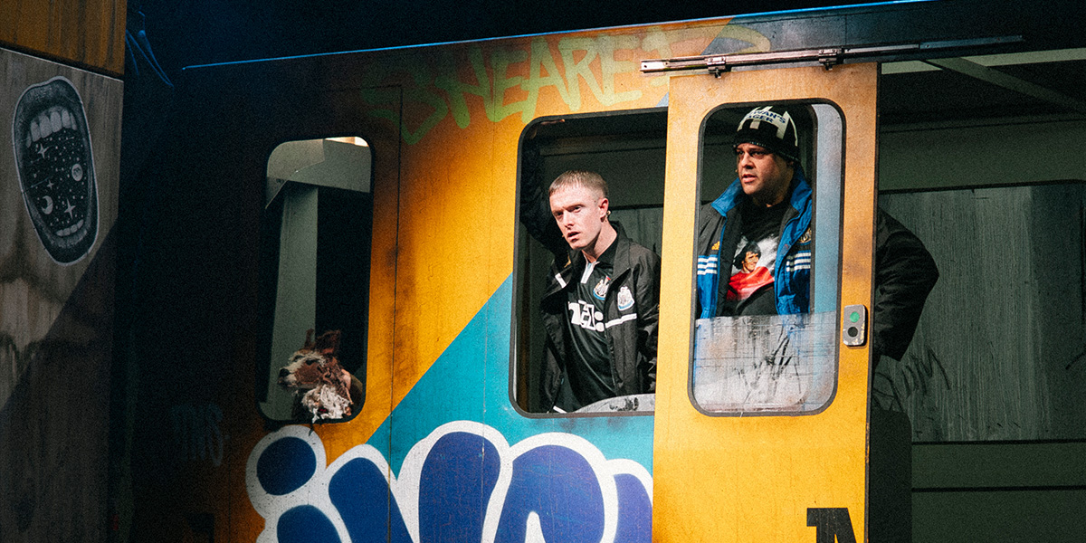 Gerry Sewell sits on a Metro train, wearing a dark jacket, surrounded by passengers and urban scenery.