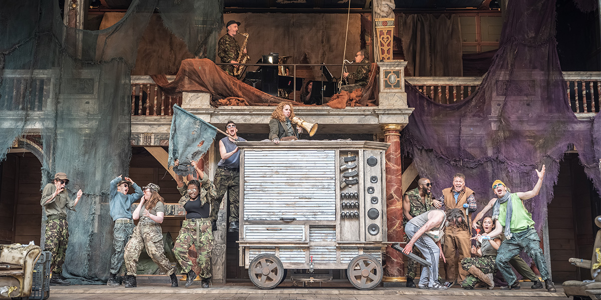 The cast of Mother Courage and Her Children performing on stage at Shakespeare's Globe, dressed in period costumes.