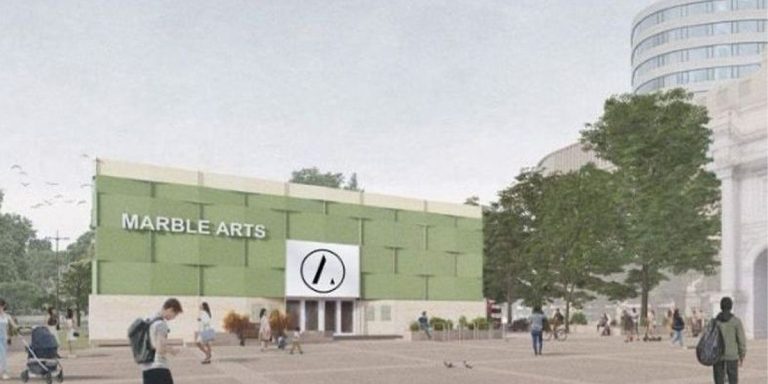 A stage at The Arts Theatre with bright lights, featuring a vibrant set design and empty seats.