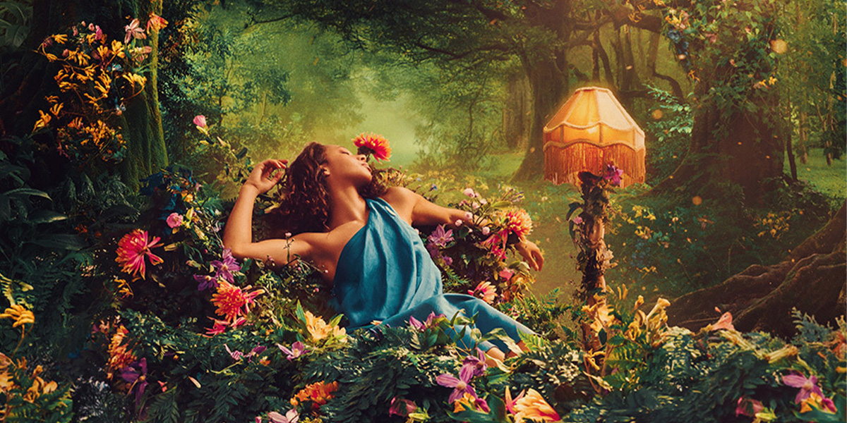 A scene from A Midsummer Night's Dream featuring actors in vibrant costumes amidst a lush forest backdrop.