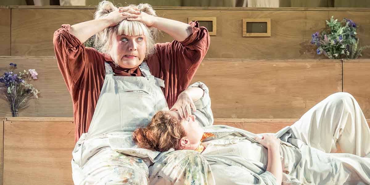 Evie Jones (Snout) looks distressed while Harriet Gordon-Anderson (Quince) lies calmly beside her on stage.