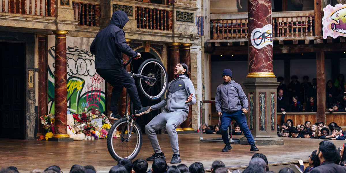 Actors performing a scene from Romeo and Juliet, dressed in period costumes, with a dramatic backdrop.