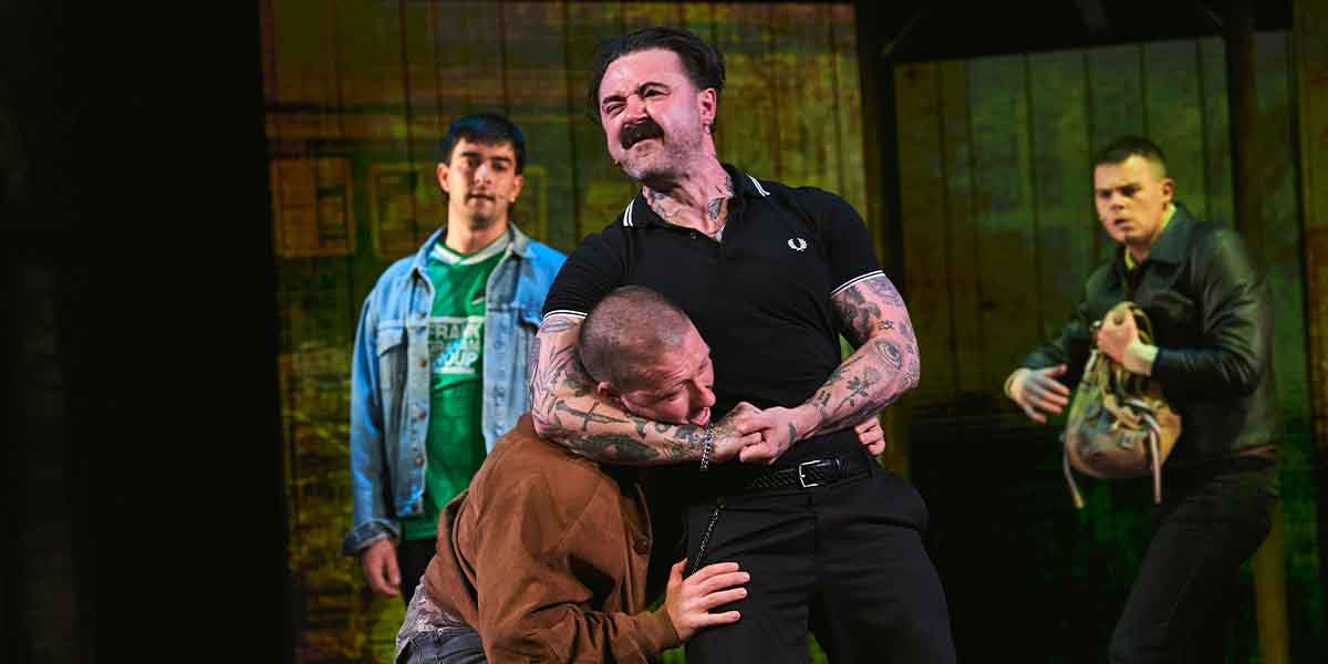 A tense scene from "Trainspotting The Musical," featuring four actors in dramatic poses and expressions.