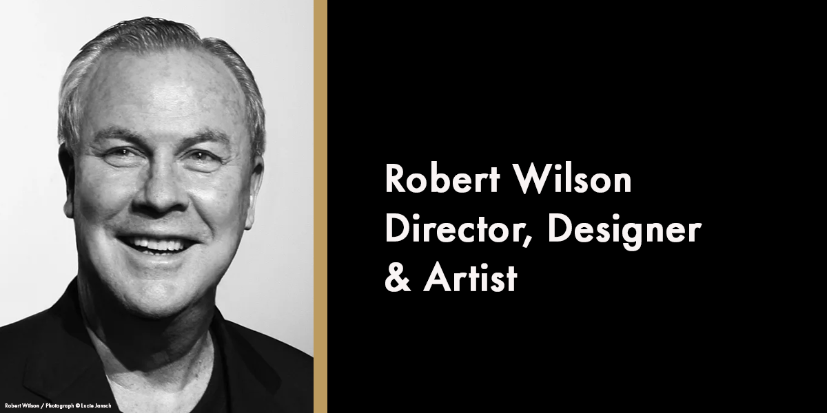 A portrait of Robert Wilson, smiling, wearing a suit against a neutral background, with a memorial date of 2026.