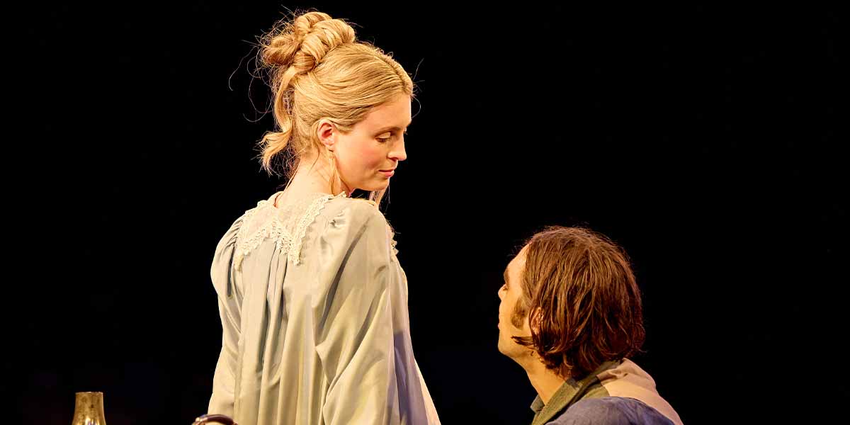 Yolanda Kettle (Lady Croom) gazes back at Seamus Dillane (Septimus Hodge) in a dimly lit setting.