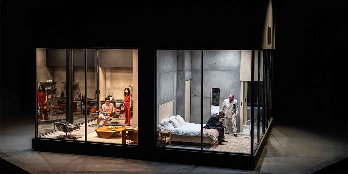 Four actors perform in a modern, split-set design, featuring a kitchen and a bedroom.
