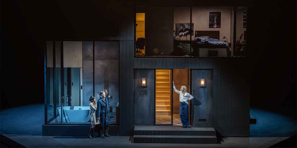 Rakhee Thakrar, David Morrissey, and Alyth Ross stand outside a modern house set in a dark stage.