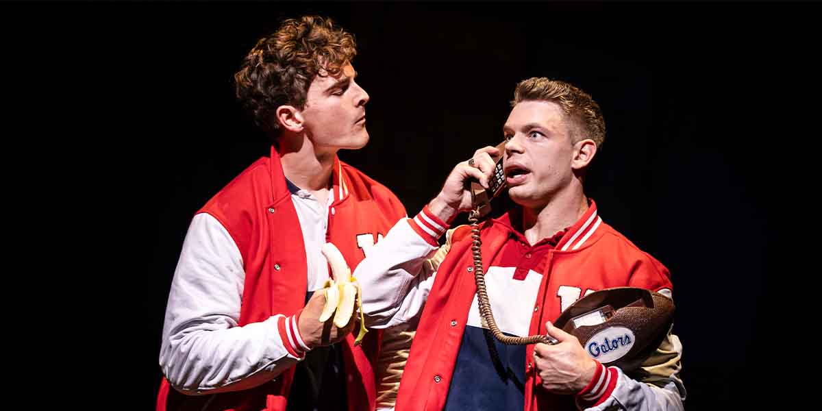 Beau Jackson holds bananas while Markus Södergren speaks on a phone, both in red varsity jackets.