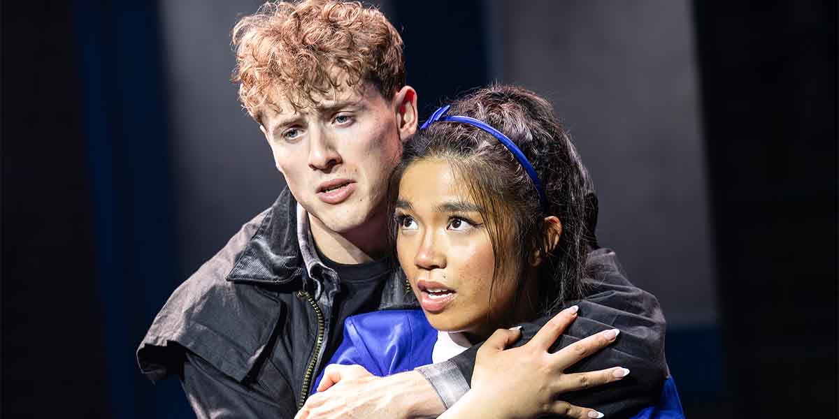 Louis Hearsey and Gerardine Sacdalan embrace, expressing emotion, with dark and blue backgrounds enhancing the scene.