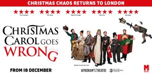 A scene from "Christmas Carol Goes Wrong" featuring actors in festive costumes, with a decorated stage backdrop.