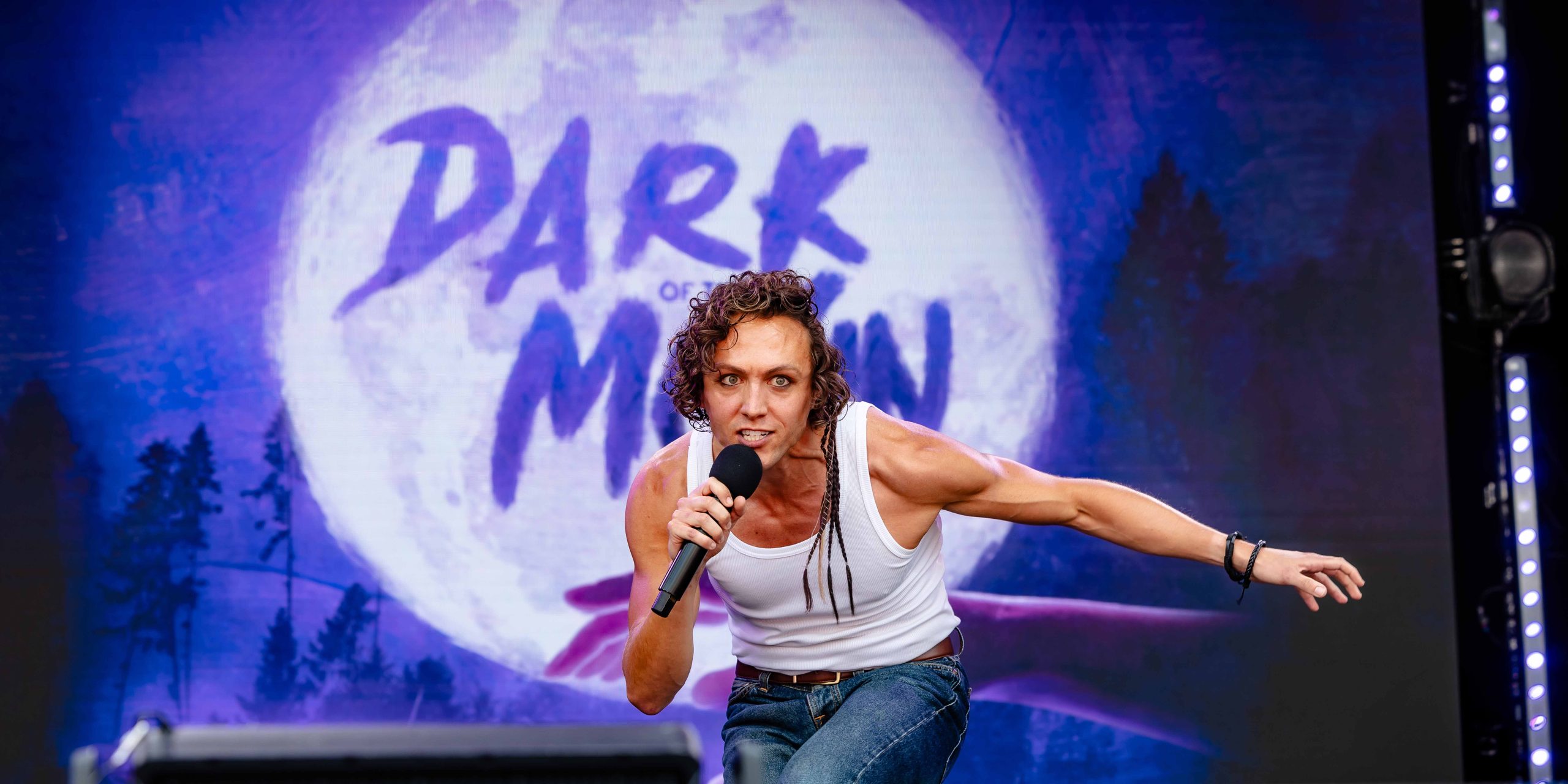Glenn Adamson performs on stage at West End LIVE 2026, wearing a dark outfit, with vibrant stage lights.