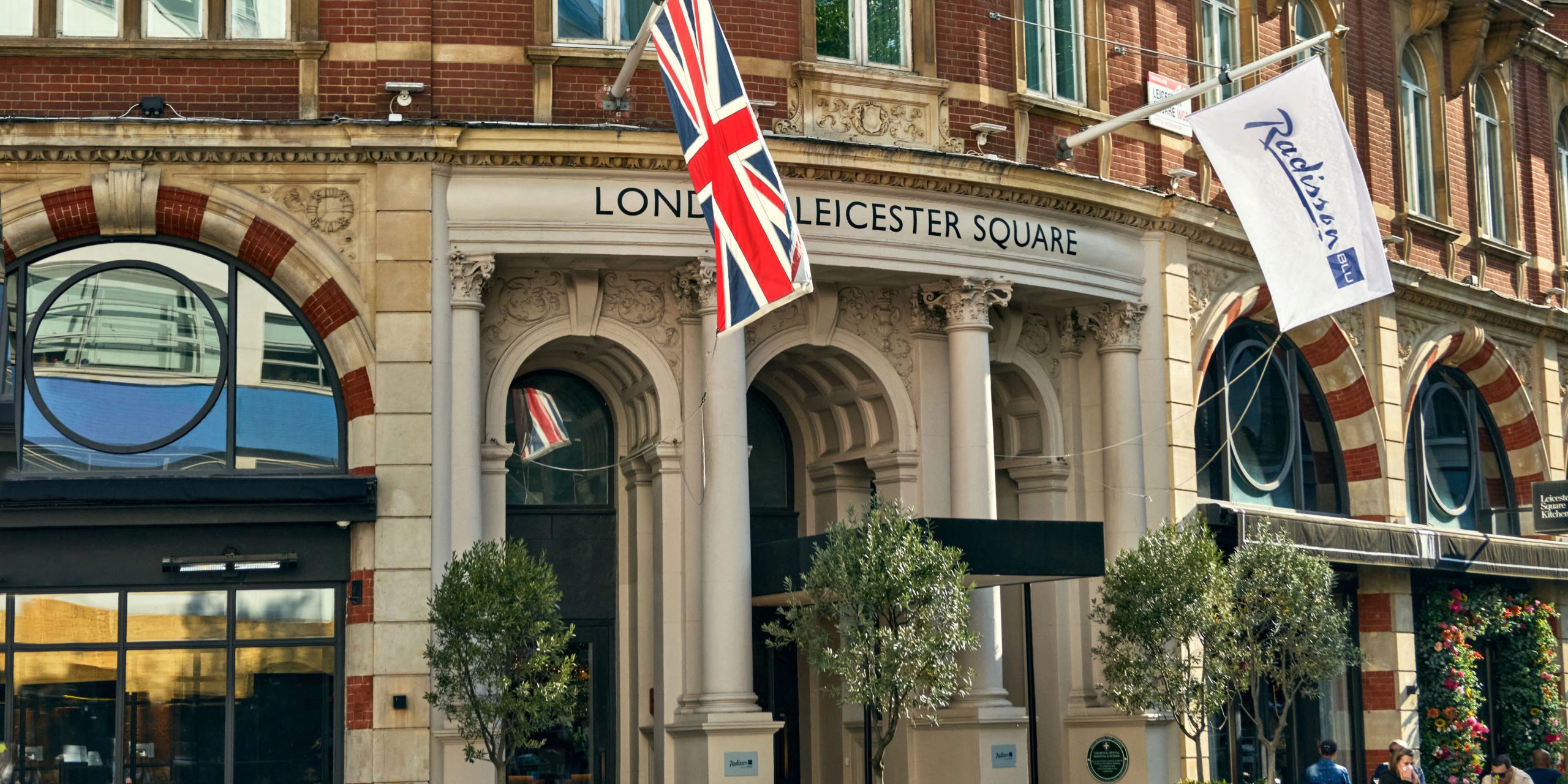 The exterior of Leicester Square Kitchen features a modern design with large glass windows and outdoor seating.