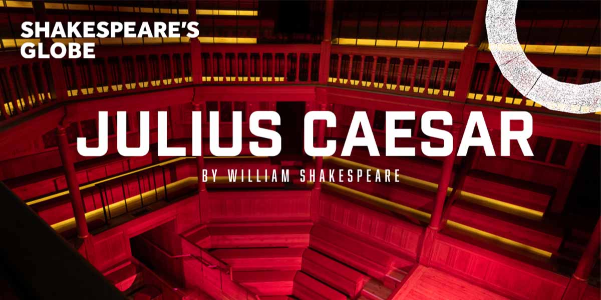 Interior of Shakespeare's Globe Theatre, featuring red lighting and text promoting "Julius Caesar" by William Shakespeare.