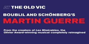 Two ticket agents assist customers at a booth, surrounded by promotional materials for Martin Guerre.